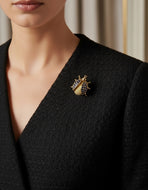 A solid 18K yellow gold ladybug pin/brooch adorned with blue sapphires.